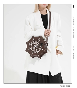 Detail einer dunkelbraunen Spinnennetz-Umhängetasche mit Stickerei am Modell