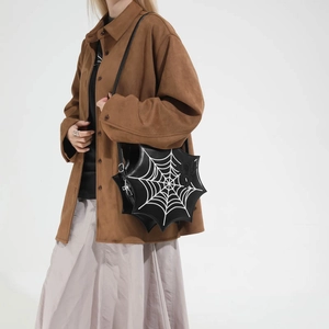 Detail der schwarzen Spinnennetz-Handtasche mit weißem Stick und 3D-Spinne