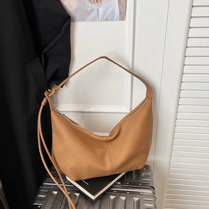 Detail of caramel large crossbody dumpling bag with pebble grain texture on luggage
