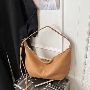 Detail of caramel leather hobo crossbody bag on a suitcase with premium texture