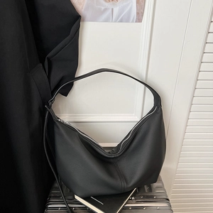 Detail of black pebbled leather hobo bag on a silver suitcase with minimalist design