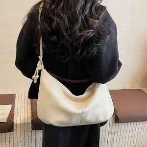Rear view of a model wearing a cream-colored large capacity leather hobo shoulder bag