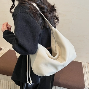 Detailed macro view of the cream-white litchi grain texture on the stylish hobo bag