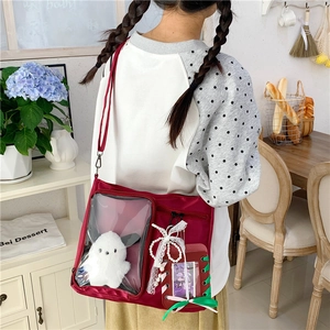Detail view of burgundy Ita bag featuring a clear window with a white bunny plush doll