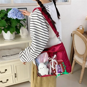 Detail of burgundy ITA bag featuring transparent window with white plush elephant charm