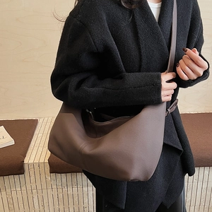 Detail view of deep brown large tote bag in soft matte leather texture on person