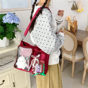 Detail of burgundy itabag with clear display window, lace trims and a green bow accent