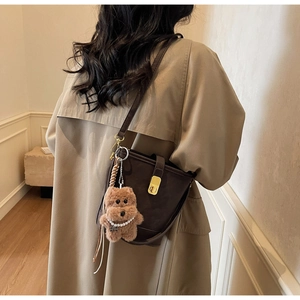 Détail du sac seau marron avec boucle dorée et pendentif ours orné de perles