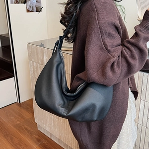 Close-up of black leather hobo bag showing soft pleats and silver metallic zipper detail
