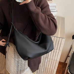 Detail of knot decoration and textured leather on a black crescent shoulder bag for women