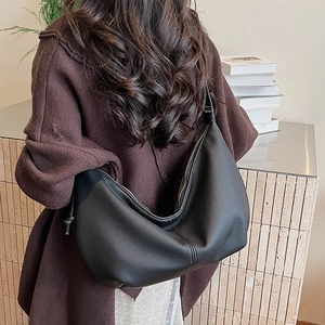 Detail view of large black lychee textured hobo bag worn with brown cardigan