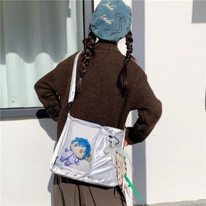 Detail of silver ita bag showing transparent PVC window with plush doll and lace ribbon decor