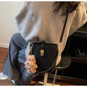 Détail d'un sac seau vintage noir avec fermoir doré et breloque en forme de nounours