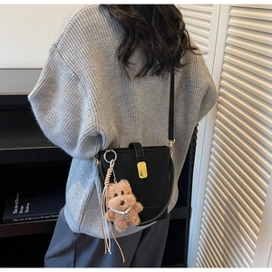 Détail d'un sac seau noir avec fermoir en métal doré et breloque ours en peluche
