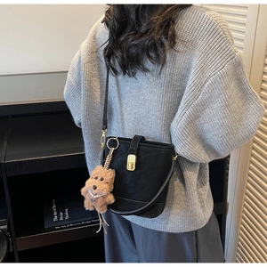 Détail d'un sac seau noir vintage avec fermoir doré et pendentif de chien en peluche