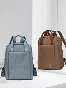 Detail view of water-resistant business backpacks in light blue and coffee with logo