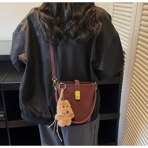 Mannequin portant un sac seau bordeaux avec charm chien en peluche et fermoir doré