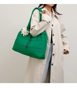 Quilted green puffer tote bag detail with white cloud charm and woven cord accents