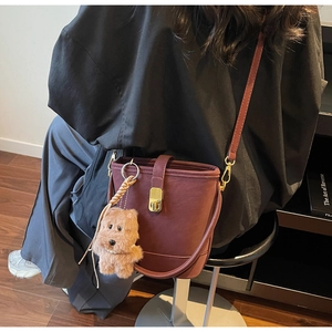 Détail du sac seau en cuir bordeaux avec fermoir doré et accessoire de breloque chiot mignon