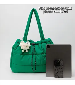 Detailed size comparison of the green quilted puffer tote bag with a tablet and phone