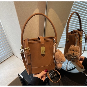 Détail d'un sac seau vintage marron avec un ourson en peluche et un fermoir doré
