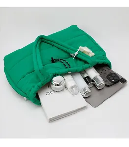 Spacious green quilted tote bag showing interior storage for books and laptop