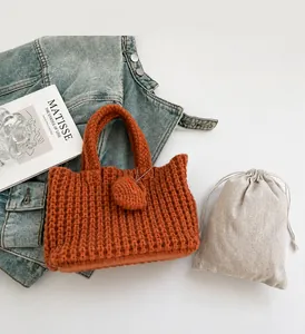 Detail of brown chunky knit handbag with a handmade leather tag and a dust bag