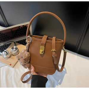 Détail du sac seau vintage caramel avec poignée supérieure et breloque ours en peluche