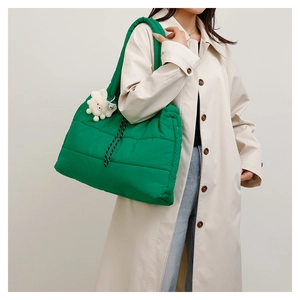 Detail of a bright green quilted puffer tote bag with decorative white plush charm