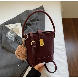 Détail du sac seau bordeaux en suédine avec fermoir doré et pendentif peluche amovible