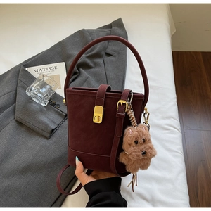 Détail d'un sac seau bordeaux en daim avec fermoir doré et pendentif peluche mignon
