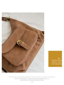 Detail view of brown textured leather bag with white contrast stitching and gold buckle
