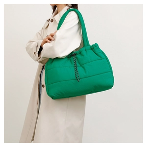 Detailed close-up of emerald green quilted tote bag with black and white braided drawstring