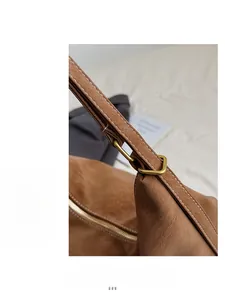 Close-up of brown leather bag shoulder strap with gold hardware and fine stitching detail