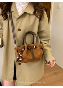 Dettaglio della borsa tote in pelle scamosciata marrone con ciondolo decorativo