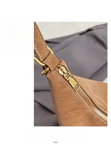 Close-up of golden metal zipper and fine stitching on the brown pebbled leather bag