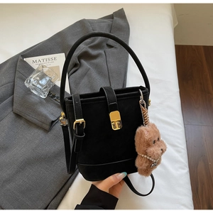 Détail du sac seau vintage noir avec fermoir doré et breloque chien en peluche