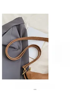Close-up of brown lychee texture leather strap with golden adjustable buckle on white cloth