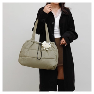 Detailed shot of olive green quilted down tote bag with plush charm and woven rope accent