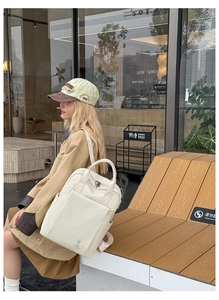 Detail of off-white quilted backpack with woven texture and rabbit logo in outdoor setting