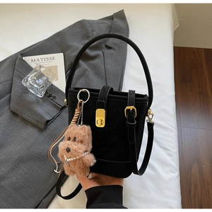 Détail d'un sac seau vintage noir avec boucle dorée et charm de chiot mignon