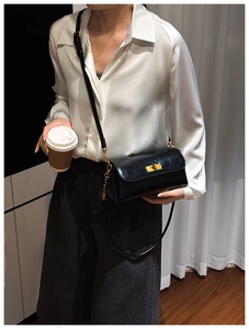 Detailed view of the black glossy leather shoulder bag with a gold metal twist lock closure