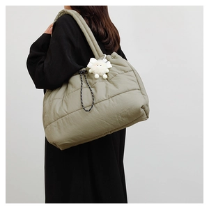 Quilted down tote bag in olive green featuring a plush monster charm on the shoulder strap