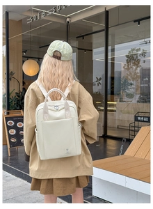 Detailed view of cream twill woven backpack with small rabbit logo in an outdoor street setting