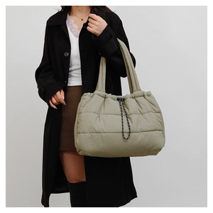 Detail showing the quilted puffer texture and black drawstring closure of the tote bag