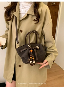 Dettaglio della borsa tote in pelle opaca caffè scuro con nappa di perle in legno