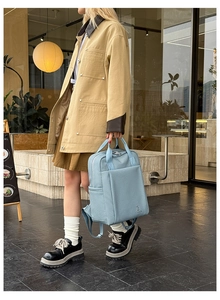 Detail of light blue business backpack with cute rabbit embroidery in a street style setting