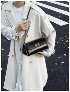 Detail shot of a dark brown glossy leather crossbody bag with a gold twist lock closure