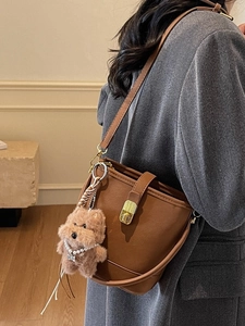 Sac seau vintage marron avec breloque chien peluche porté comme un sac à bandoulière