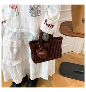 Close-up of a handmade dark brown knitted handbag featuring a unique heart-shaped tag detail